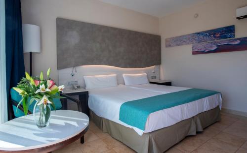 a hotel room with a bed and a vase of flowers at Impressive Playa Granada Golf in Motril