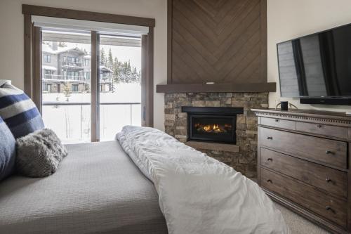 een slaapkamer met een bed, een open haard en een televisie bij Gateway Condo - 15 Wildwood in Big Sky
