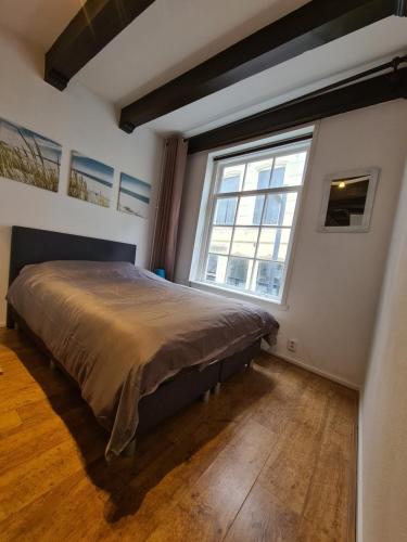 a bedroom with a large bed and a large window at Rijksmonument Havenzicht, met zeezicht, ligging direct aan zee en centrum in Vlissingen