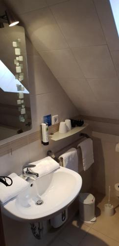 a white bathroom with a sink and a mirror at Airport Hotel One Aparthotel Sylt in Tinnum