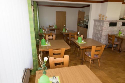 ein Restaurant mit Holztischen und -stühlen und einem Kamin in der Unterkunft Hotel Grünes Paradies- Garni in Hochwaldhausen