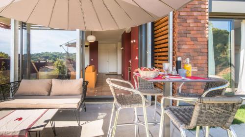 un patio avec une table, des chaises et un parasol dans l'établissement 100% Relax avec Jacuzzi Privatif, à Sarlat-la-Canéda