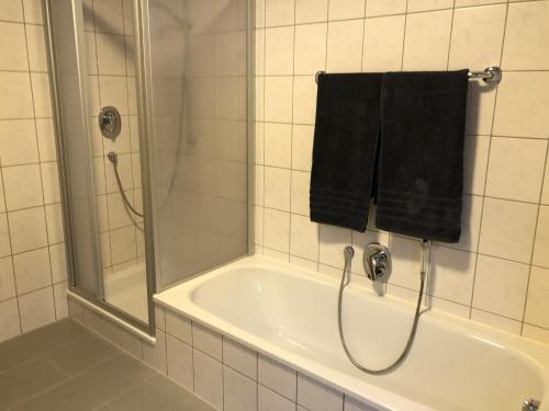 a bath tub with a shower and a black towel at Ferienwohnung Jasmin in Haiger