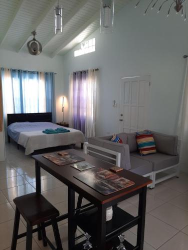 a bedroom with a bed and a table and a couch at CC Best Villas Tobago in Lowlands