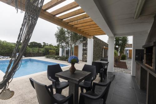 a patio with a table and chairs next to a swimming pool at Quinta das Giestas in Ribeira Grande
