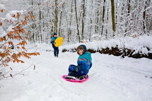 a child on a snowboard in the snow with a person in the background at Winiec Family Houses in Winiec