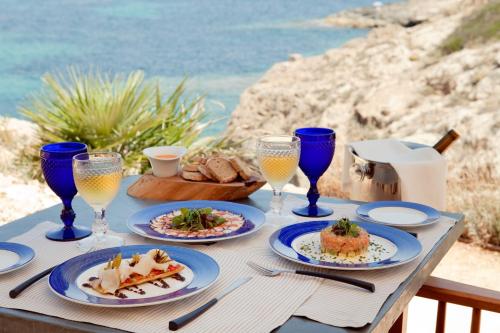 a table with plates of food and glasses of wine at Cap Rocat, a Small Luxury Hotel of the World in Cala Blava