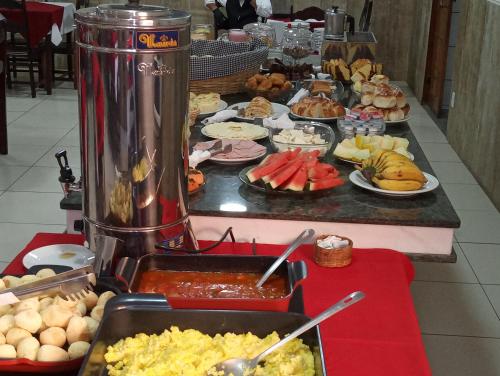 a buffet of food on a table with a blender at Hotel Alzira Imperial in São Lourenço