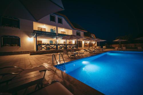 a swimming pool in front of a house at night at Pensiunea Briza Marii Jurilovca in Jurilovca