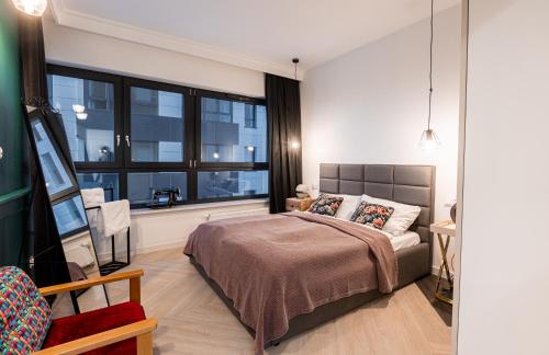 een slaapkamer met een bed en een groot raam bij E&A Royal Luxury Apartments, Bydgoszcz - SKYLINE in Bydgoszcz