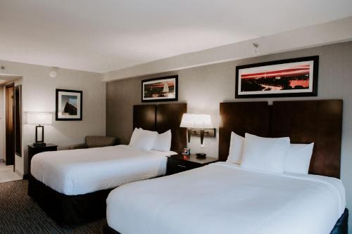 two beds in a hotel room with white sheets at Wingate by Wyndham - Dulles International in Chantilly