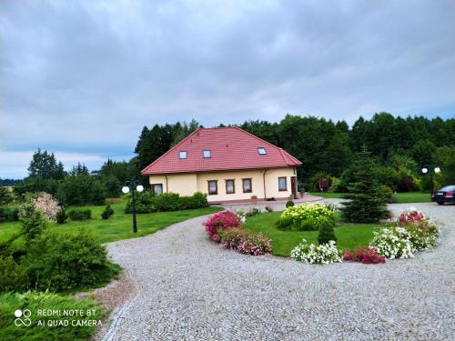 ein Haus mit rotem Dach auf einer Kieseinfahrt in der Unterkunft Cichy Zakątek in Krzynowłoga Mała