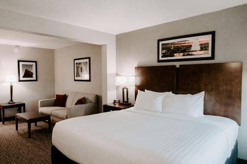 a hotel room with a large bed and a chair at Wingate by Wyndham - Dulles International in Chantilly
