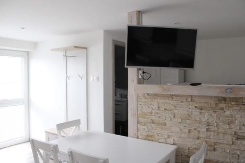 sala de estar con mesa blanca y TV en la pared en Ubytovanie Ľaľa, en Spišské Tomášovce