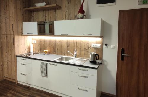 a kitchen with white cabinets and a sink at Apartmán Hrebienok Rezort A307 in Starý Smokovec