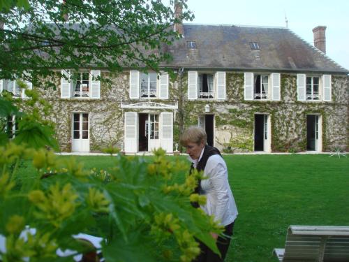 a woman standing in front of a large house at La Maison Blanche in Cuvergnon