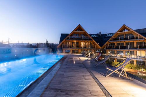 a large swimming pool with a building in the background at APARTHOTEL ROYAL RESORT SPA Zakopane in Zakopane