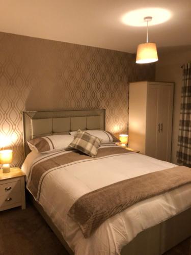 sypialnia z dużym białym łóżkiem z 2 lampami w obiekcie Bruxie Holiday Cottages - Honeysuckle Cottage w mieście Maud
