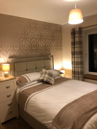 sypialnia z łóżkiem i ścianą ze wzorem w obiekcie Bruxie Holiday Cottages - Honeysuckle Cottage w mieście Maud