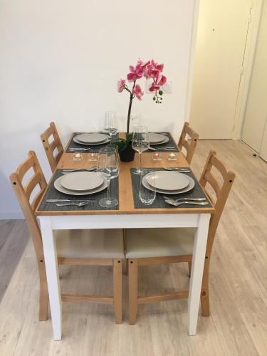 a table with plates and glasses and a vase with flowers at HOUSE COSY ONE in Gonesse