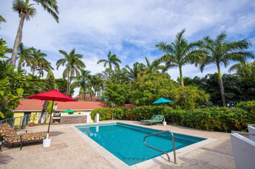 a swimming pool with two chairs and a red umbrella at Harbour View Boutique Hotel & Wellness Retreat in Belize City