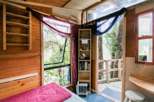 a bedroom with a bed and a large window at The Treehut in Island Bay