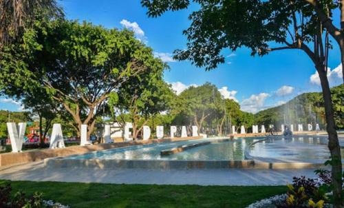 a fountain in a park with trees and grass at Apartamentos Las Piloneras in Valledupar