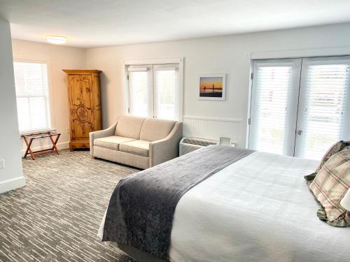a bedroom with a bed and a couch and a chair at Harbor House Inn in Grand Haven