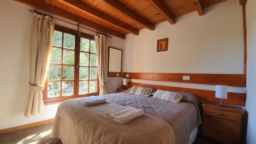 a bedroom with a bed with two towels on it at Cabañas & Aparts Lancuyen, Villa de Montaña in Villa La Angostura