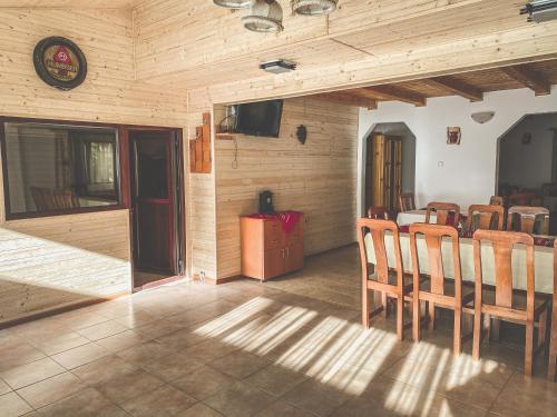 a dining room with wooden walls and a table and chairs at Pensiunea Ionela in Zemeş