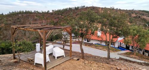 a wooden deck with white chairs and a house at Monte Corgo da Vaca in Sabóia