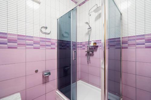 a bathroom with a shower with pink and purple tiles at Apartments Zrno in Cavtat