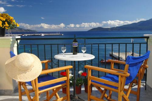 a table with two chairs and a bottle of wine on a balcony at Alexis Studios and Apartments in Ayia Evfimia