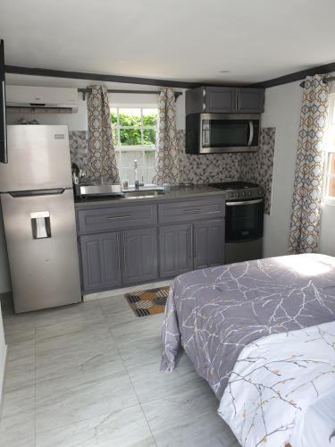 een keuken met een bed, een koelkast en een wastafel bij Devachan Apartments in Bridgetown