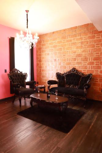 a living room with leather furniture and a brick wall at Casa Rosa Hotel & Spa in San Cristóbal de Las Casas