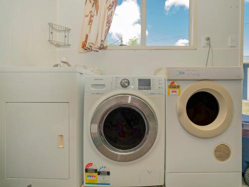 a washing machine and a dryer in a room at Daze Away - Cooks Beach Holiday Home in Cooks Beach