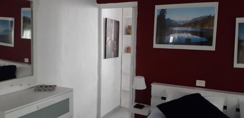 SardinaにあるFaro de sardina Apartmentの白いベッドと赤い壁が備わるベッドルーム1室が備わります。