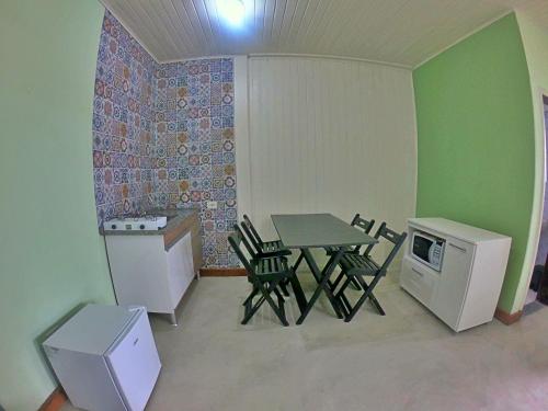 Habitación pequeña con mesa, sillas y nevera. en Kitnet Com Ar, em frente a Praia de Boracéia en São Paulo