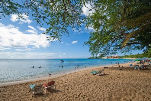 a beach with chairs and people in the water at Casa Valeria Boutique Hotel in Sosúa