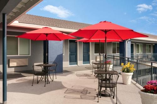 a patio with tables and chairs with red umbrellas at Torch Lite Inn at the Beach Boardwalk in Santa Cruz