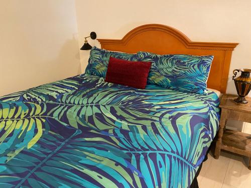 a bed with a colorful comforter and a red pillow at Villa Rosa Inn in Santa Barbara