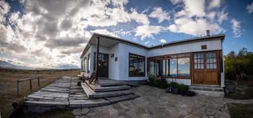 una casa blanca con una pasarela de madera delante de ella en Estancia Cerro Guido, en Torres del Paine