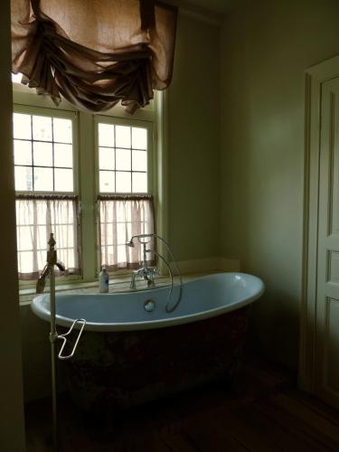 a bath tub in a bathroom with two windows at B&B Saint-Sauveur Bruges in Bruges