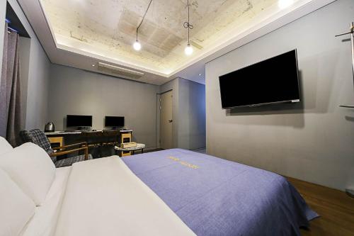 a hotel room with a bed and a desk and a tv at Hotel Myeongjak in Chuncheon