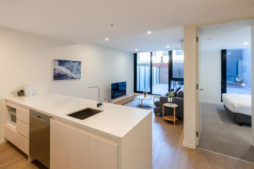 a kitchen and living room with a couch and a bed at Melbourne City Apartments - Teri in Melbourne