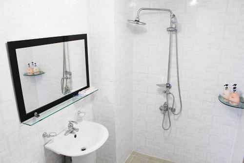 a white bathroom with a shower and a sink at HY Choi Hostel in Seogwipo
