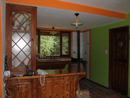 cocina con paredes verdes y encimera de madera en Hostel Meridiano 71 en El Bolsón