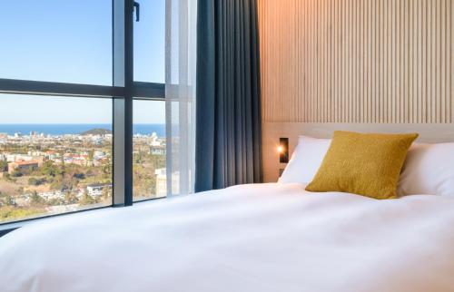 a bedroom with a white bed and a large window at Ventimo Hotel & Residence Jeju in Jeju