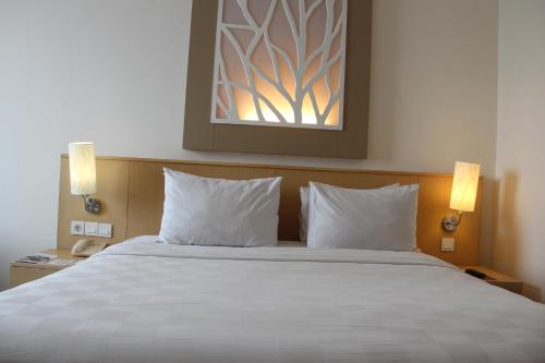 a bedroom with a large bed with two pillows at Swiss-Belinn Manyar in Surabaya