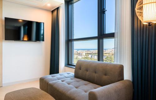 a living room with a couch and a large window at Ventimo Hotel & Residence Jeju in Jeju